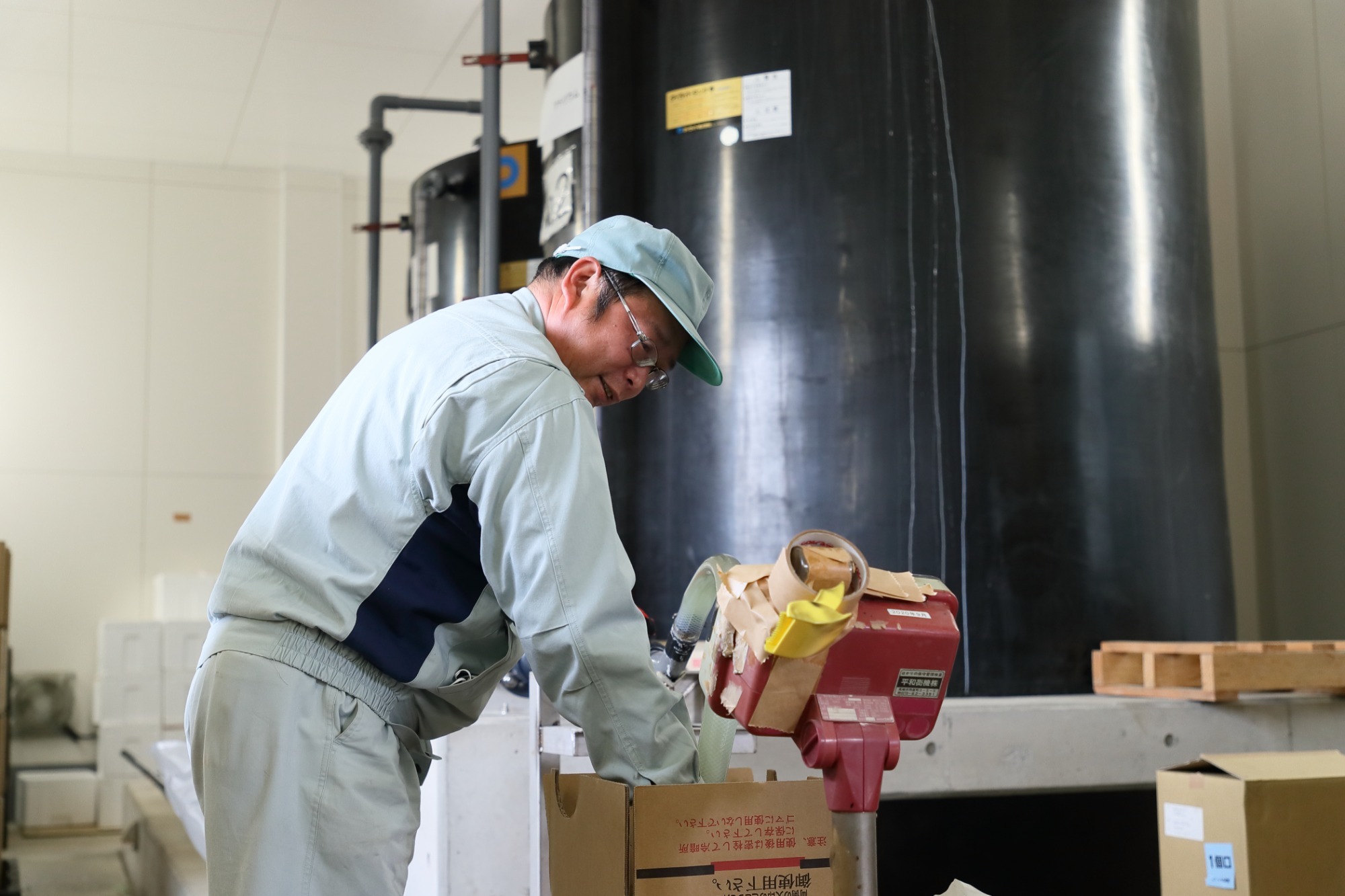 写真：男性作業員が次亜塩素酸ナトリウムを梱包しているところ